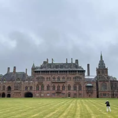 Château historique en Écosse entouré d’un vaste parc verdoyant sous un ciel nuageux.