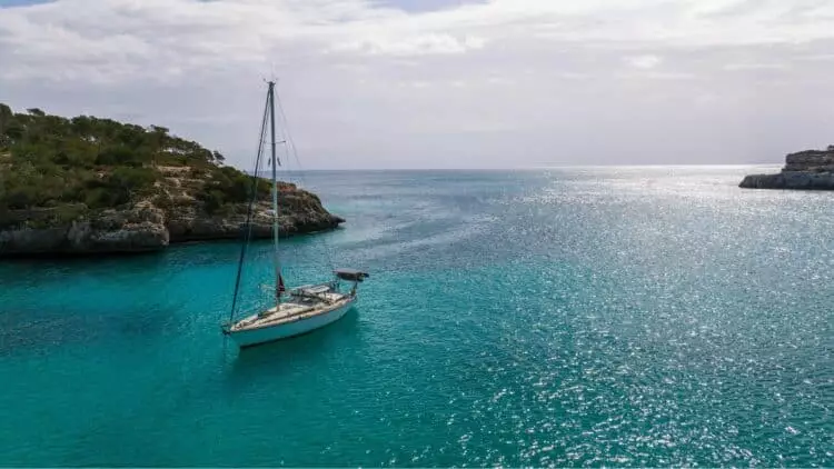 Voilier ancré dans une calanque aux eaux turquoise entourée de falaises