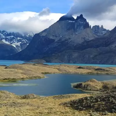 Paysage du parc national Torres del Paine au Chili avec lac turquoise, montagnes rocheuses et sommets enneigés.
