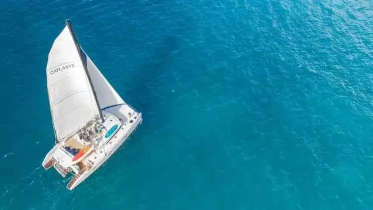 Catamaran à voile naviguant sur une mer turquoise vu du ciel lors d’une croisière