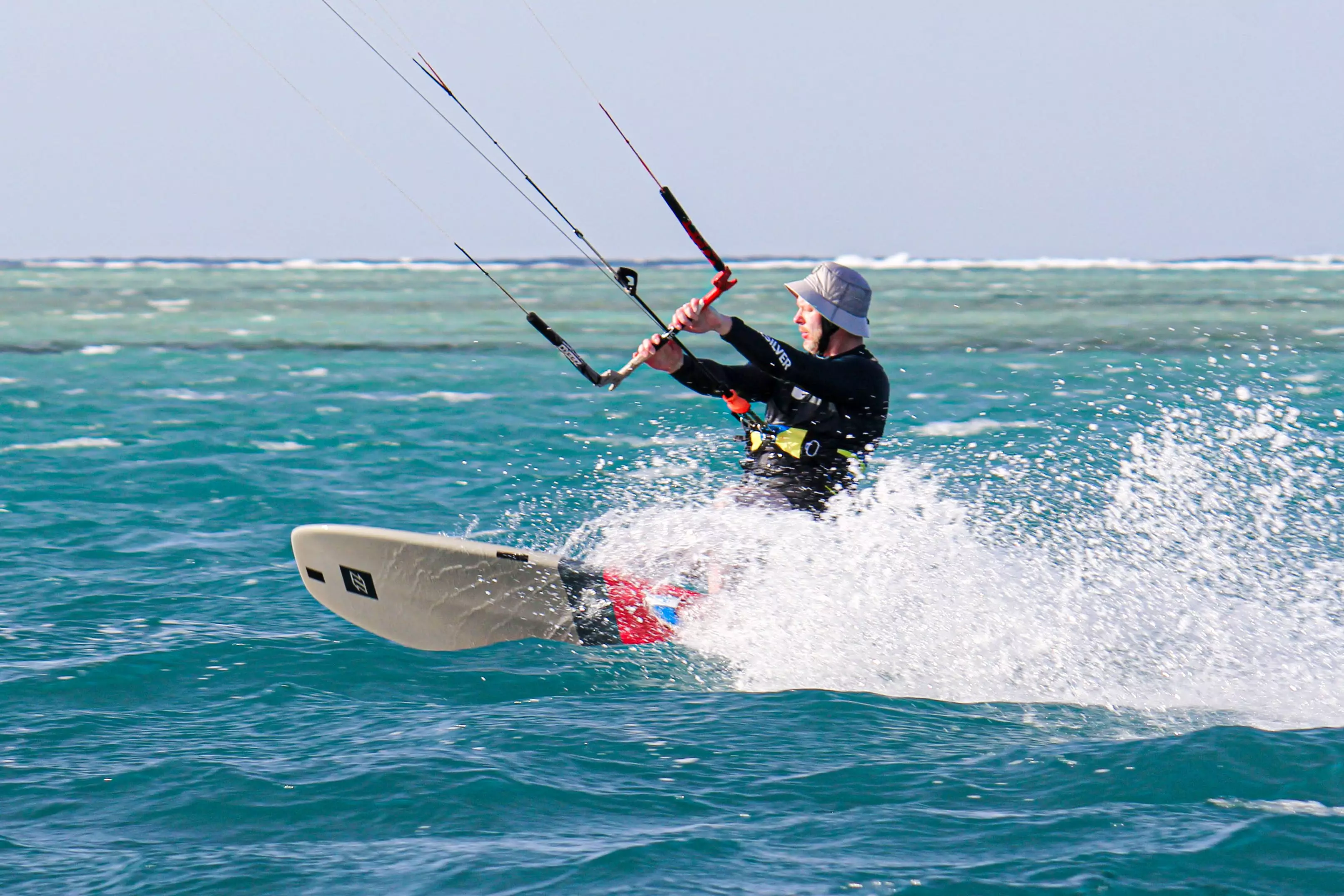 Pratiquant de kitesurf naviguant sur une eau turquoise lors d’un séjour sportif en bord de mer tropicale.