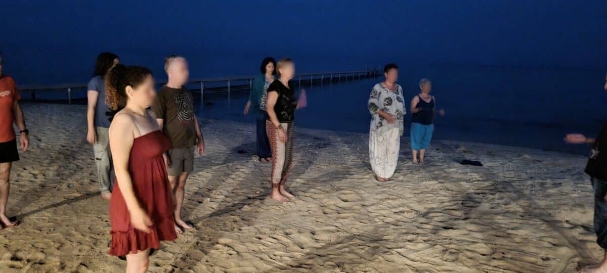 Groupe pratiquant le Qi Gong sur une plage au coucher du soleil en Égypte.