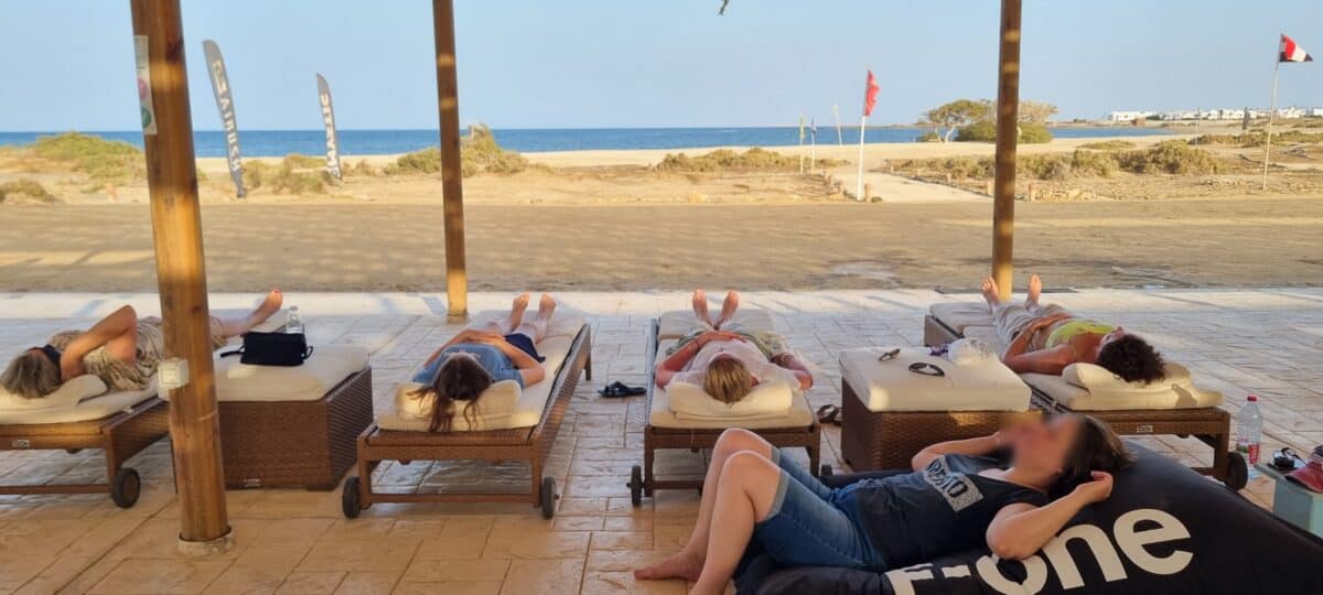 Groupe en pleine relaxation allongé sous une pergola en bord de mer.