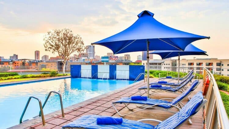 Piscine extérieure d'un hôtel à Johannesburg avec vue sur la skyline de la ville.