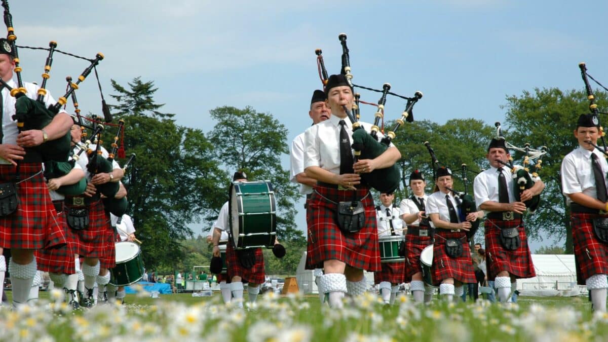 Groupe de musiciens écossais en kilt jouant de la cornemuse lors d’un événement en plein air