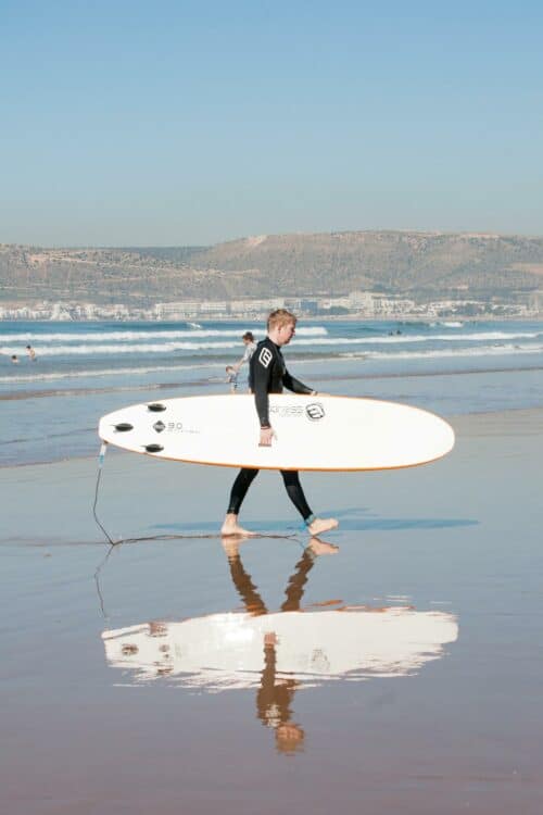 Surfeur marchant sur une plage avec une planche de surf au Maroc