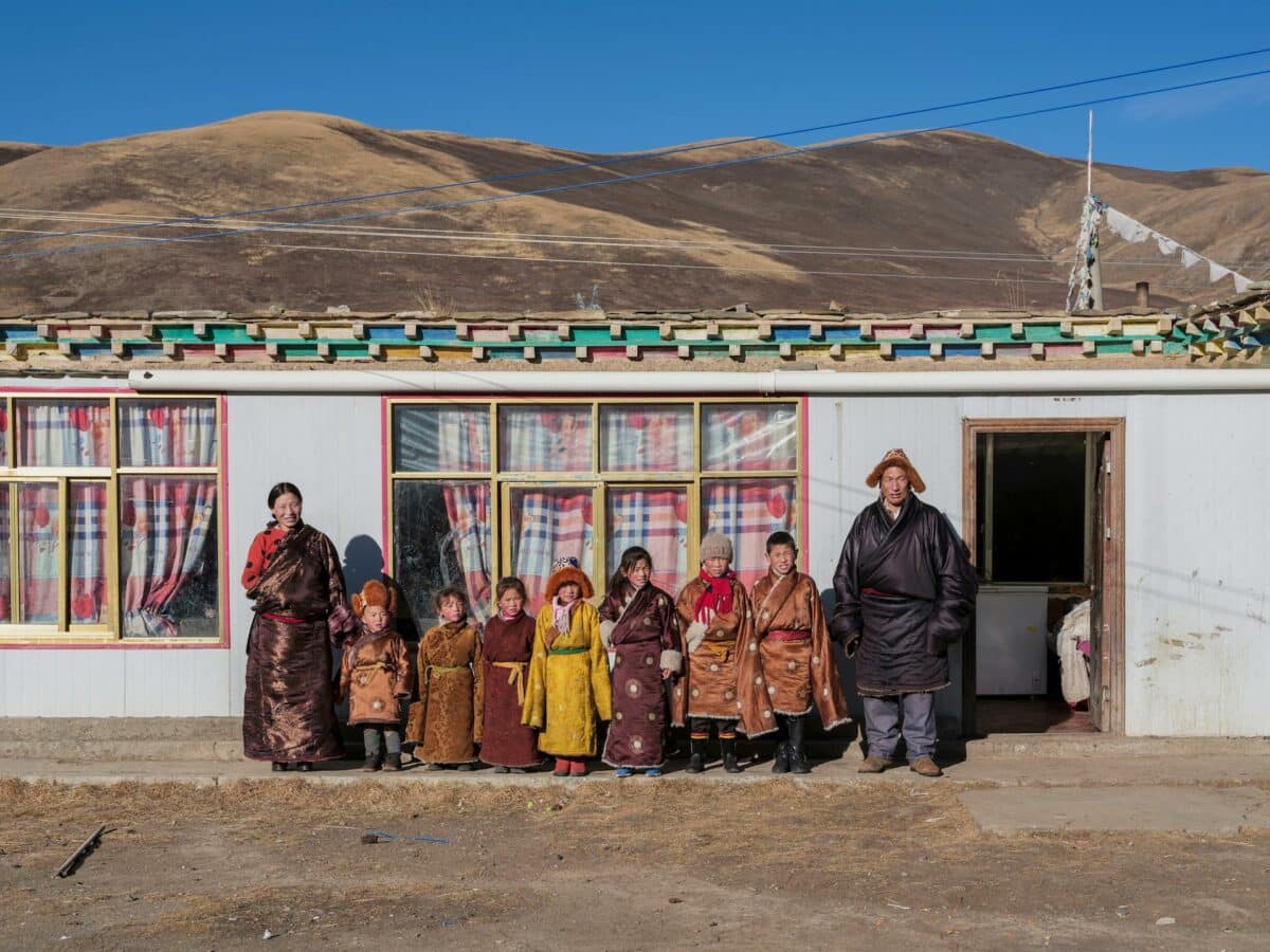 Famille mongole en tenues traditionnelles devant leur maison.