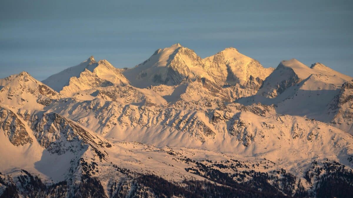 Sommets enneigés des Alpes suisses éclairés par la lumière dorée du soleil couchant