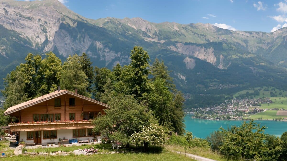 Chalet traditionnel suisse avec vue sur un lac turquoise et un village alpin