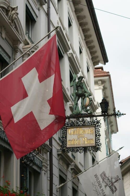 Drapeau suisse accroché à la façade d’un hôtel traditionnel en centre-ville