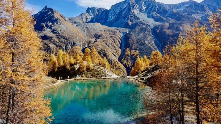 Lac alpin suisse aux eaux turquoise entouré de montagnes et de forêts aux couleurs d’automne