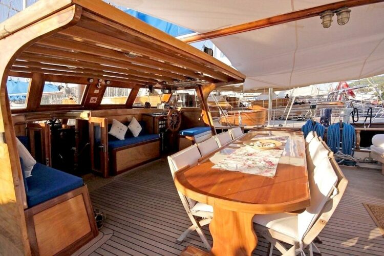 Pont arrière d’un voilier en bois avec espace de dîner pour une croisière en petit bateau en Grèce