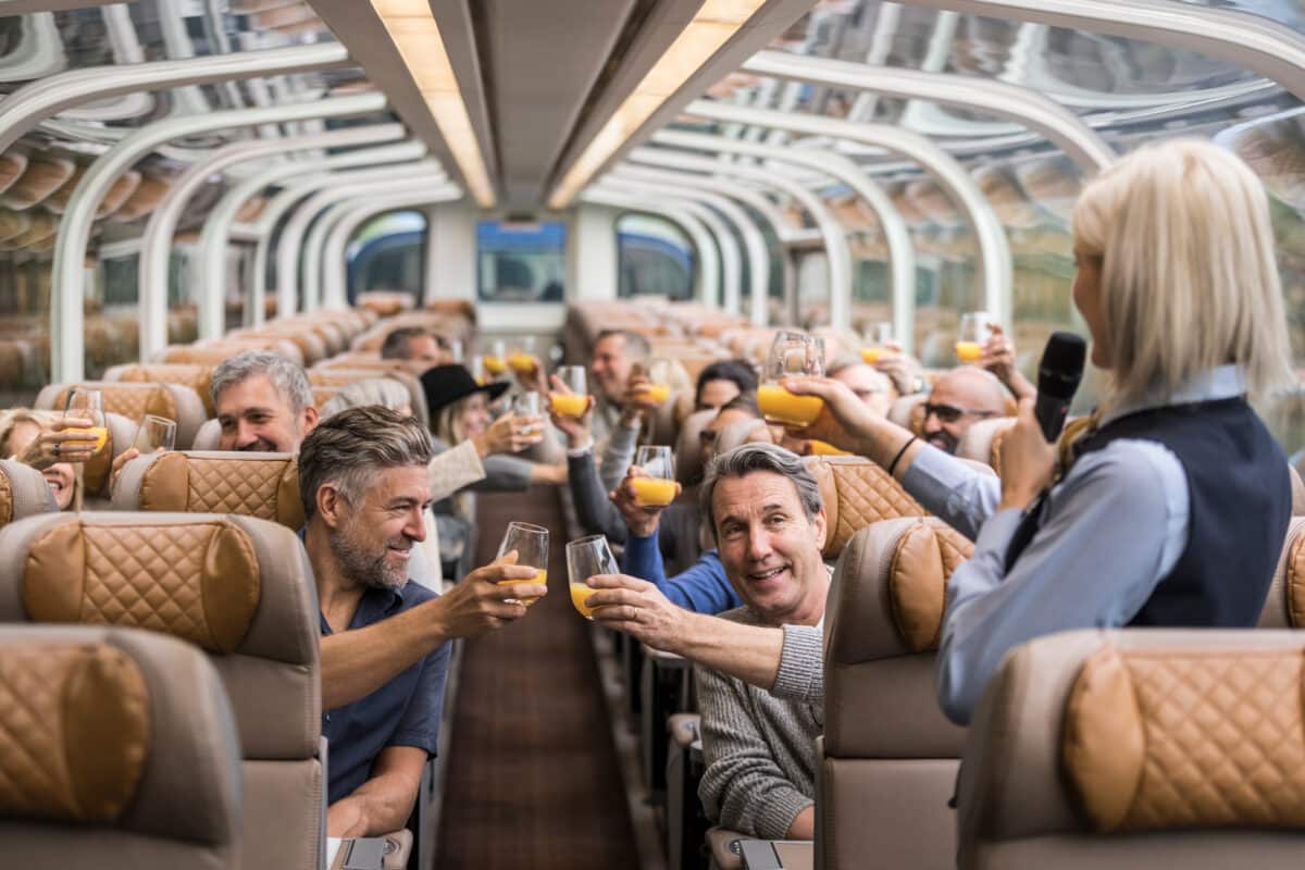 Ambiance chaleureuse et service haut de gamme à bord du train Rocky Mountaineer avec des passagers trinquant.