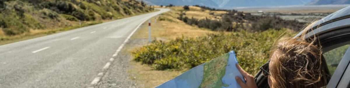 Femme consultant une carte lors d’un road trip à travers les paysages sauvages de Norvège en été.