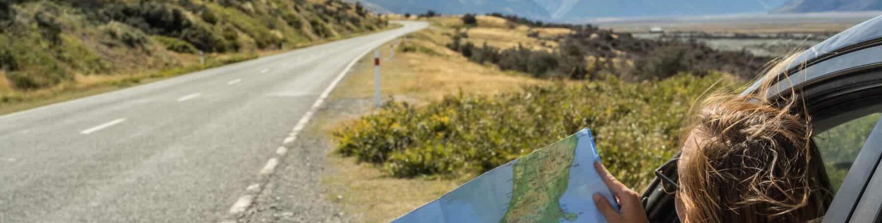 Femme consultant une carte lors d’un road trip à travers les paysages sauvages de Norvège en été.