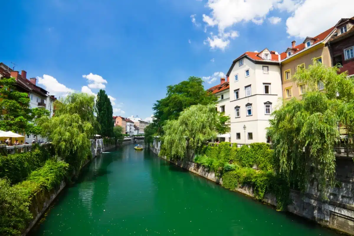 Canal verdoyant de Ljubljana bordé de maisons anciennes et d’arbres