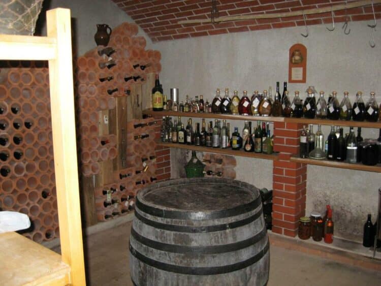 Cave à vins artisanale d’une ferme slovène avec tonneau rustique et collection de spiritueux