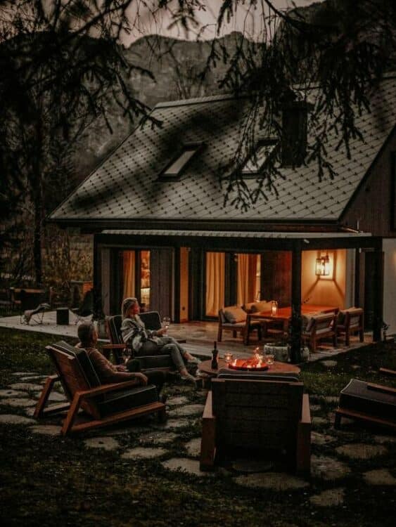 Deux personnes se détendent autour d’un feu de camp devant un chalet de montagne en Slovénie