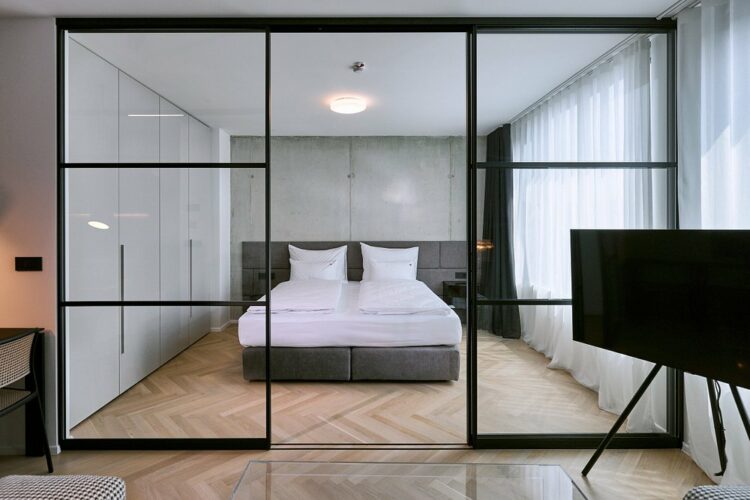 Chambre moderne et lumineuse avec lit double et grandes baies vitrées