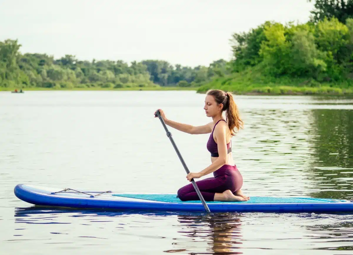 Femme pratiquant le yoga sur un paddle au milieu d’un lac