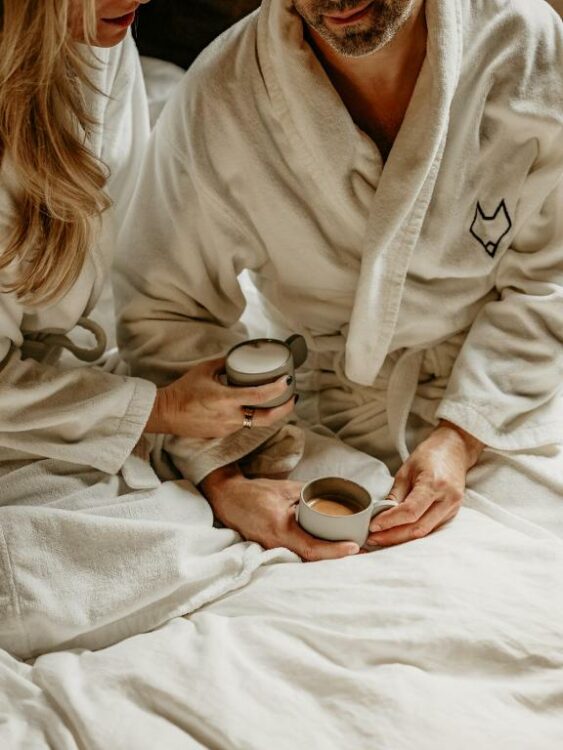 Couple dégustant un café au lit en peignoir dans un hébergement de charme