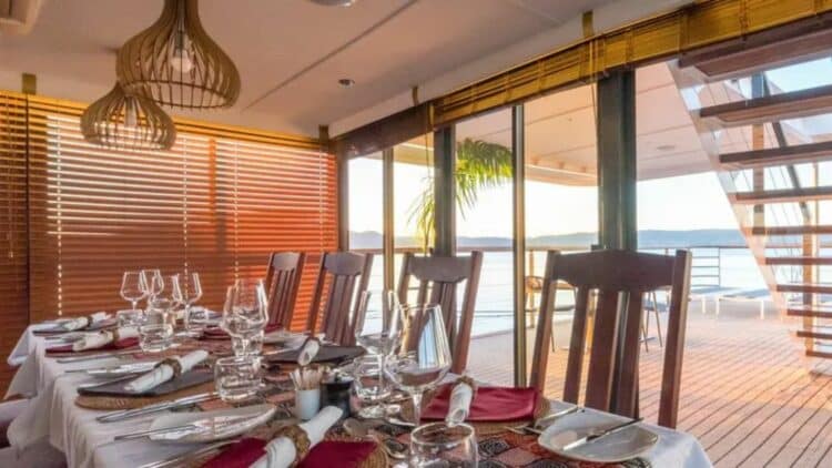 Salle de restaurant du bateau African Dream avec table dressee et vue sur le fleuve africain.