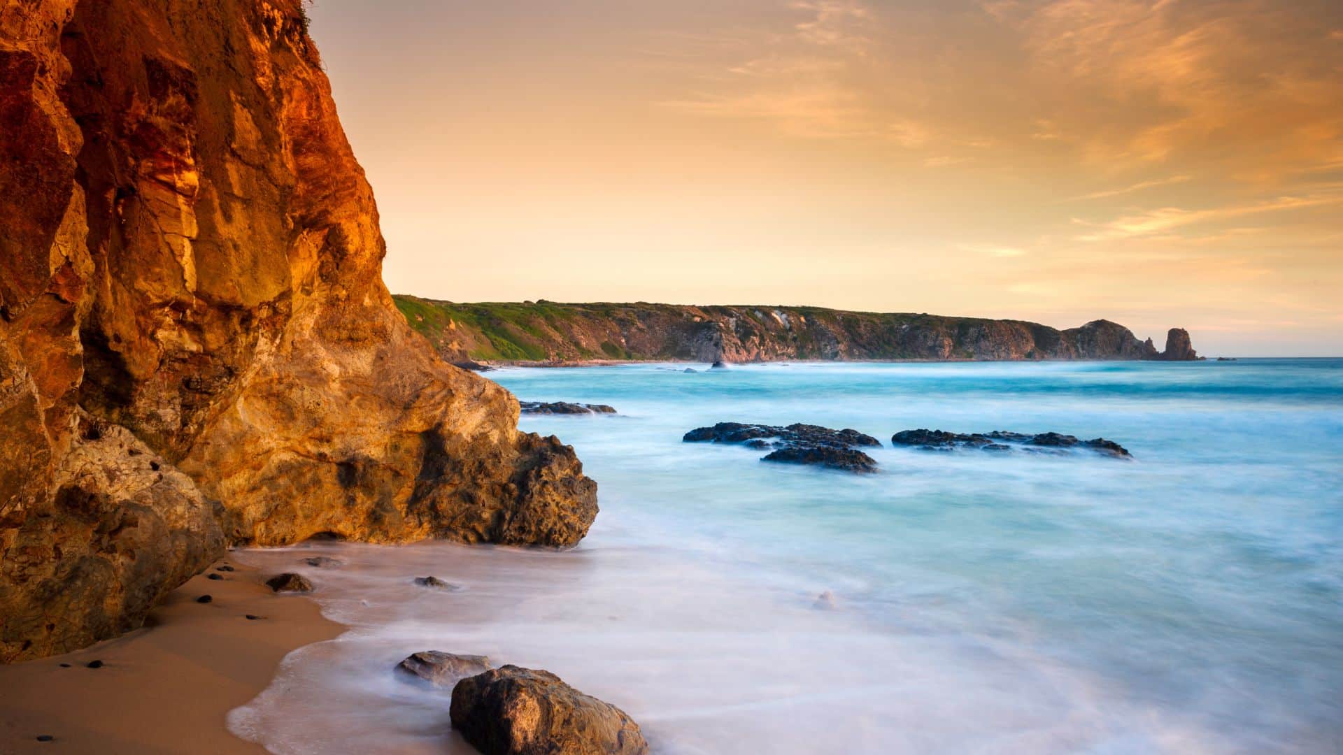 Côte rocheuse sauvage en Australie avec plage de sable et falaises au coucher du soleil