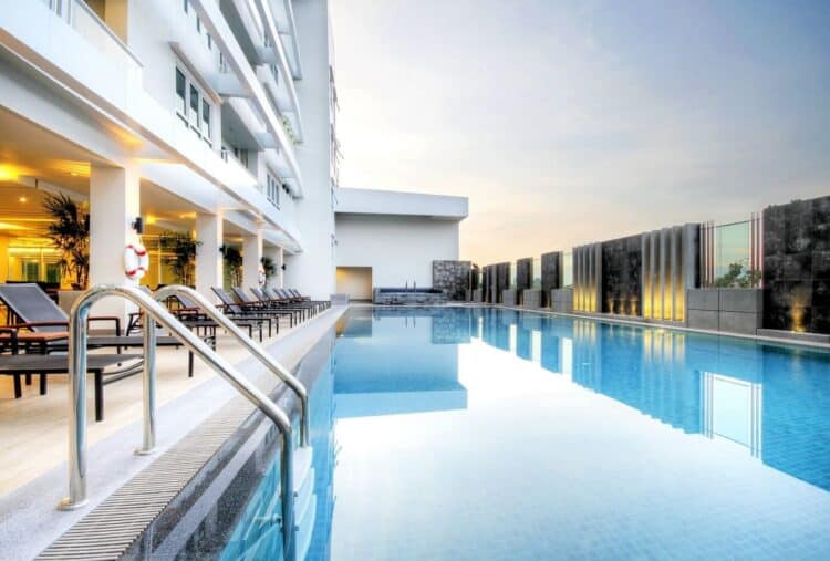Piscine extérieure de l’hôtel Classic Kameo à Bangkok avec transats et architecture moderne
