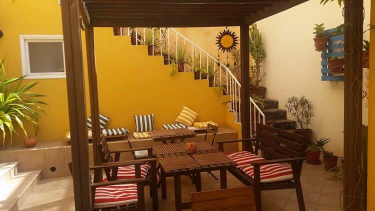 Patio et espace détente du Kira’s Boutique Hotel au Cap-Vert avec tables et coussins colorés.