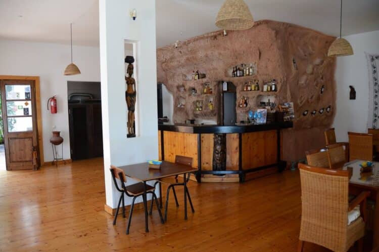 Espace de restauration de Pipi’s Guesthouse au Cap-Vert avec bar et tables en bois.