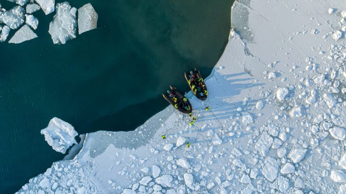 Zodiacs d’expédition accostant sur la banquise avec un groupe de voyageurs équipés au Groenland.