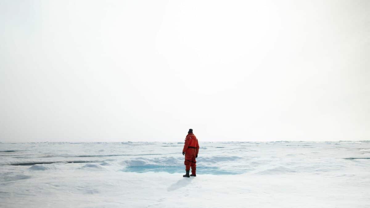 Explorateur en combinaison polaire marchant seul sur la banquise au Groenland.