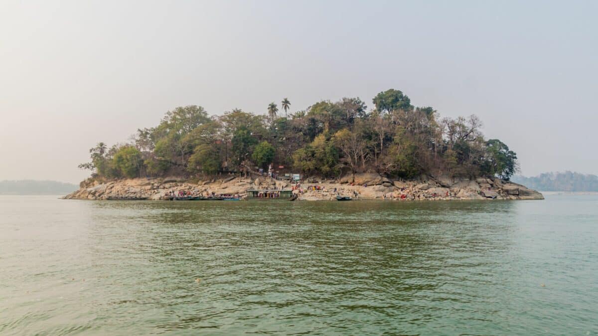 Île boisée sur le fleuve Brahmapoutre avec des visiteurs arrivant en bateau près de Guwahati.