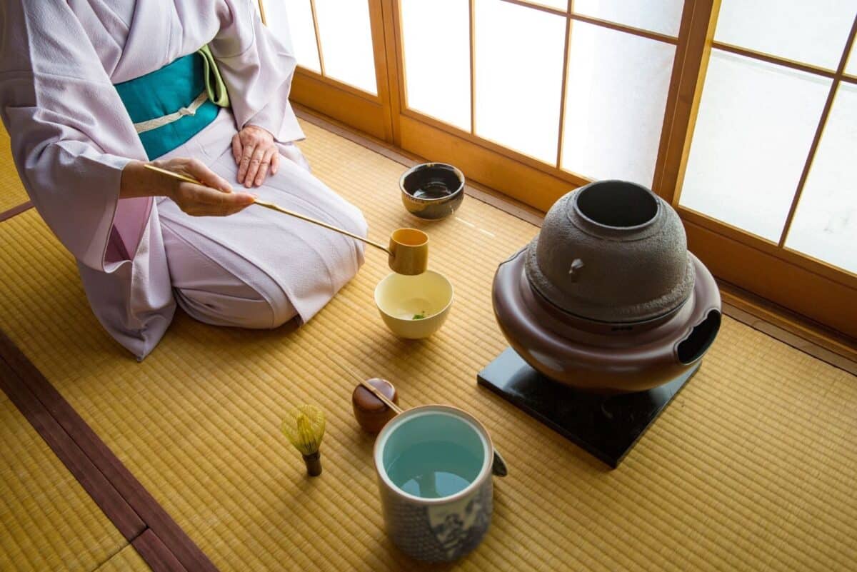 Cérémonie du thé traditionnelle au Japon avec maître de thé en kimono préparant le matcha sur tatami.