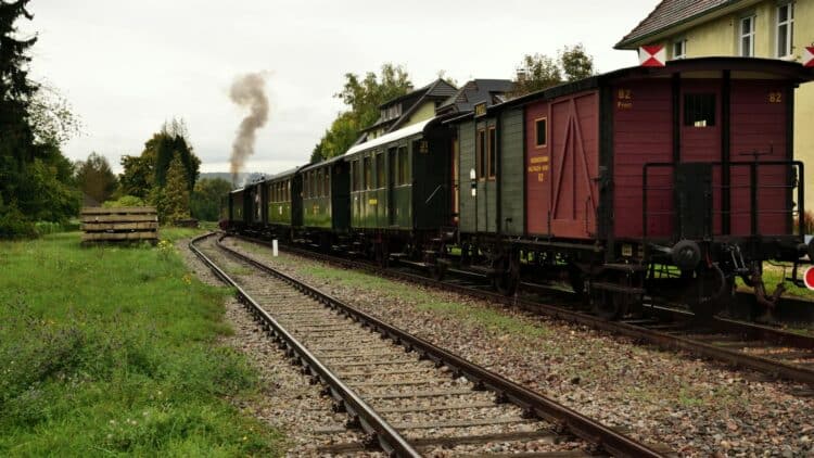Train historique circulant à travers la campagne lituanienne sur une voie ferrée bordée de verdure