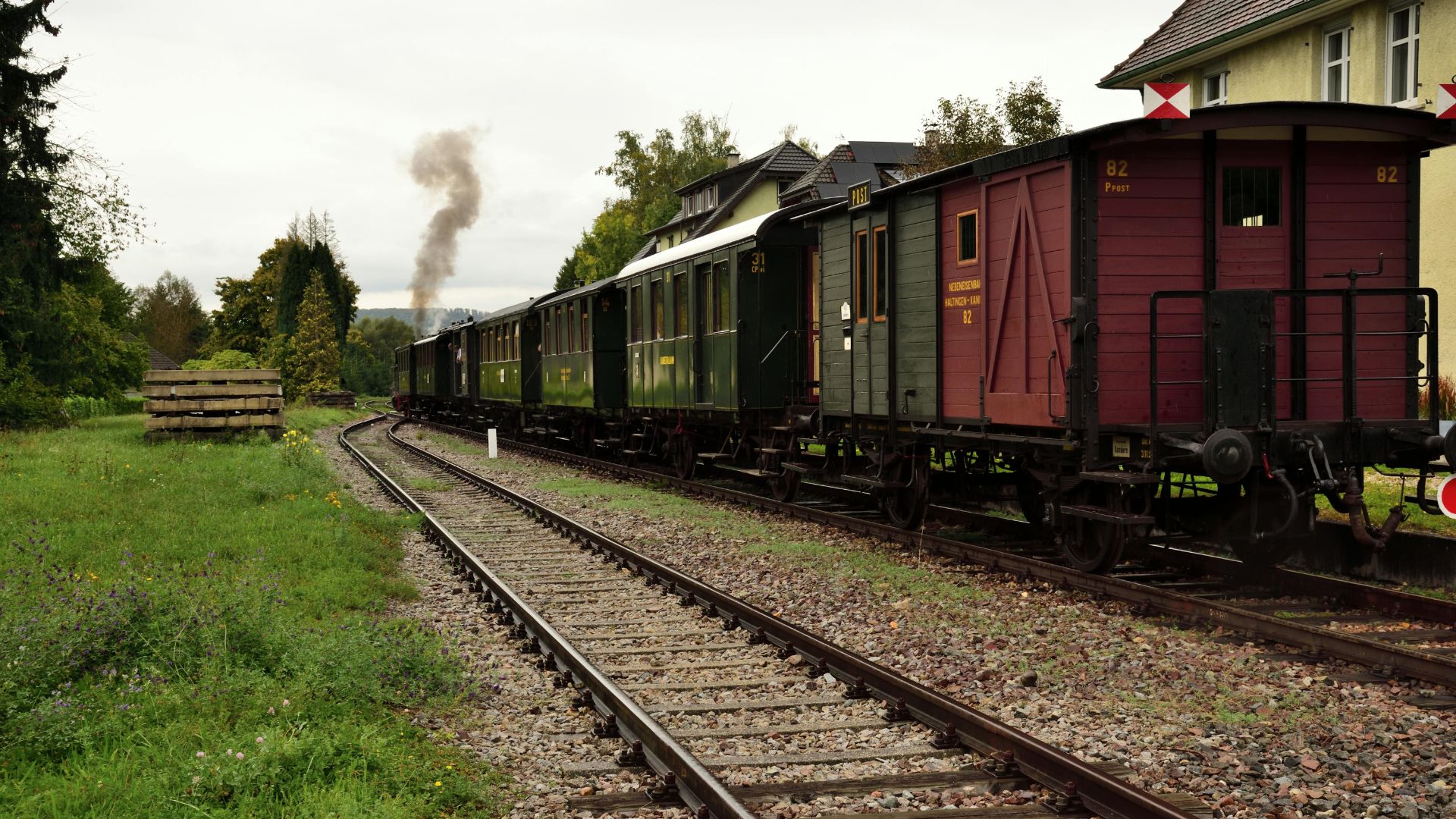 Train historique circulant à travers la campagne lituanienne sur une voie ferrée bordée de verdure