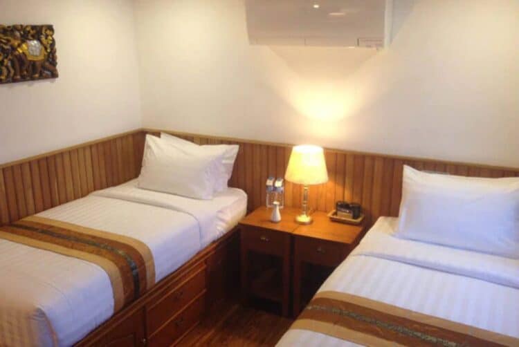 Cabine twin avec deux lits simples à bord d’un bateau naviguant sur le Mékong.