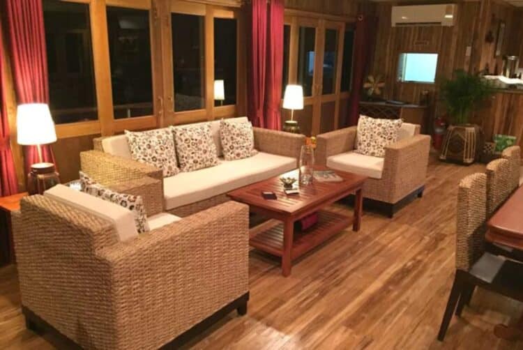 Salon intérieur d’un bateau de croisière sur le Mékong avec fauteuils en rotin et décoration en bois.