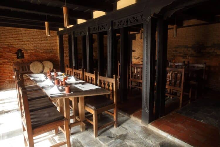 Salle de restaurant traditionnelle népalaise avec tables en bois et murs en briques