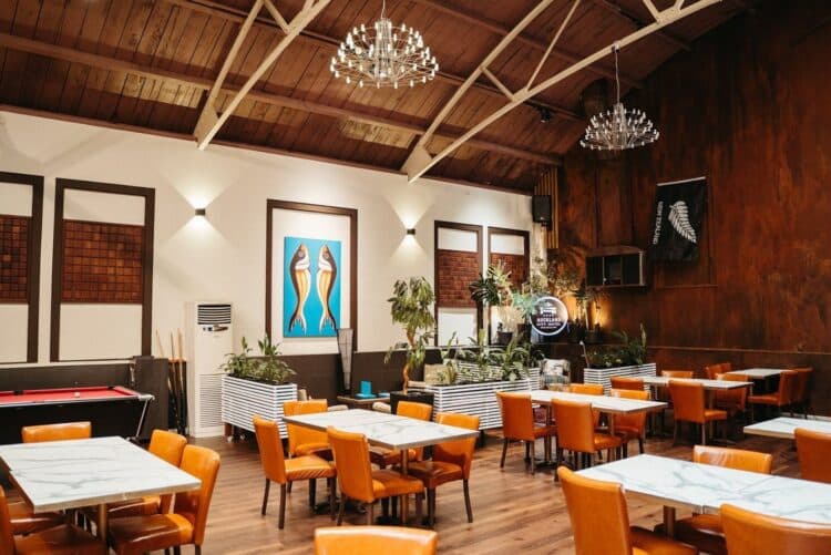 Salle de restaurant moderne de l’Auckland City Hotel en Nouvelle-Zélande avec tables et décoration boisée.