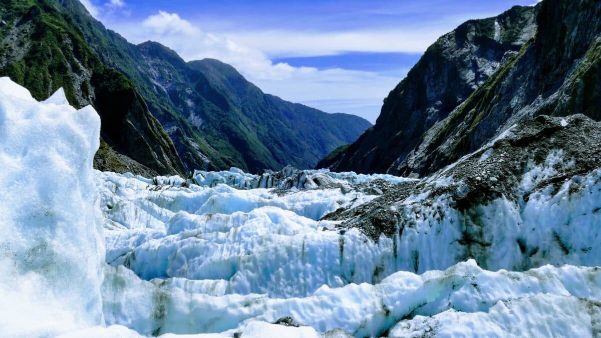 Glacier alpin entouré de montagnes escarpées en Nouvelle-Zélande sur la côte ouest.
