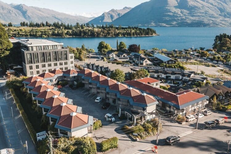 Vue aérienne du Blue Peaks Lodge à Queenstown en Nouvelle-Zélande avec lac et montagnes en arrière-plan.