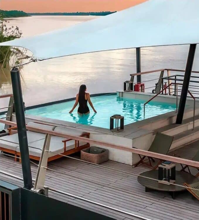 Piscine sur le pont superieur du bateau Aqua Nera avec vue sur le fleuve en Amazonie peruvienne au coucher du soleil.
