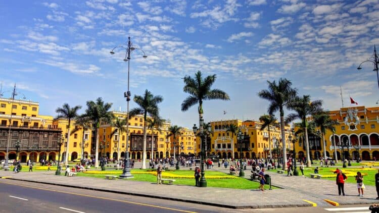 Place historique de Lima avec batiments coloniaux jaunes, palmiers et visiteurs dans le centre-ville.