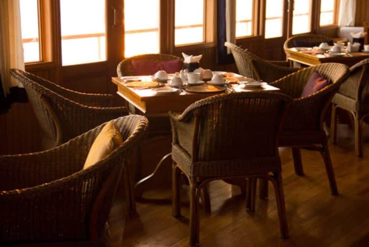 Salle de restaurant avec tables dressées et grandes fenêtres à bord du RV Kindat Pandaw.