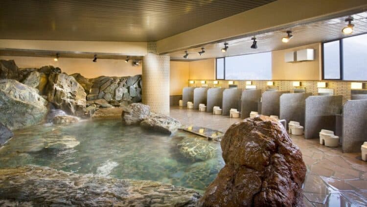 Onsen intérieur dans un ryokan japonais avec bassin thermal entouré de pierres naturelles