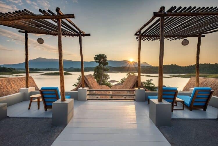 Terrasse avec transats face au lac Nam Ngum au coucher du soleil.