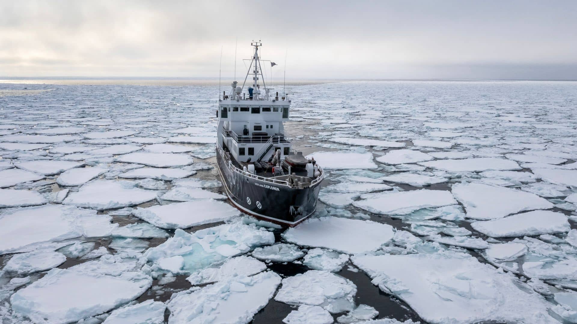 Navire d’expédition naviguant au milieu de la banquise au Spitzberg, entouré de plaques de glace dérivantes en Arctique.