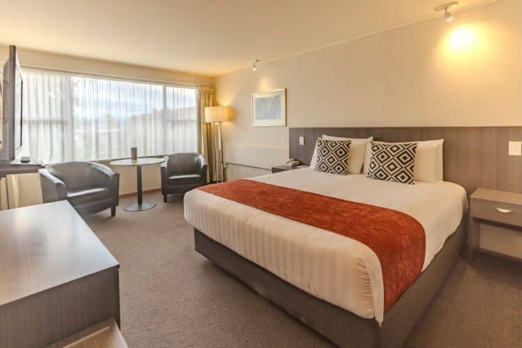 Chambre double confortable au Kingsgate Hotel Te Anau avec grand lit, coin salon et baie vitrée lumineuse.