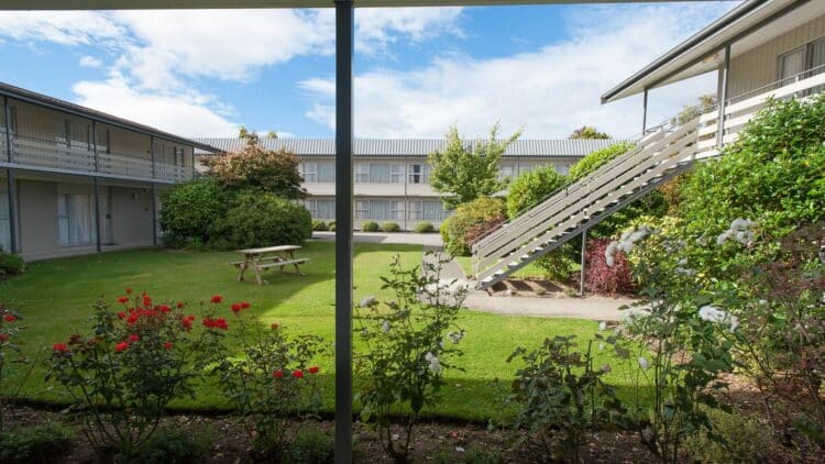 Extérieur du Kingsgate Hotel Te Anau avec bâtiment sur deux niveaux entouré d’un jardin verdoyant.